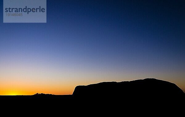 Blick vom Aussichtspunkt bei Sonnenaufgang auf die Silhouette des Uluru Ayers Rock mit dem Sonnenuntergang hinter Kata Tjuta The Olgas