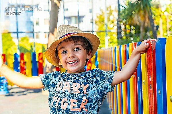 Porträt eines fröhlichen Jungen mit Hut  der auf einem Spielplatz spielt