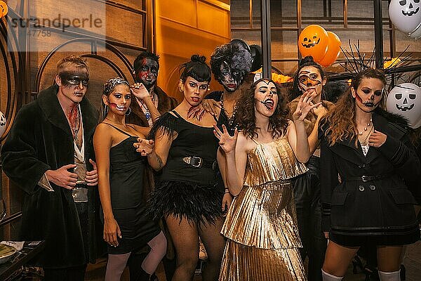 Halloweenparty mit Freunden in einer Diskothek  eine Gruppe von Freunden sitzt geschminkt und kostümiert auf einem Sofa