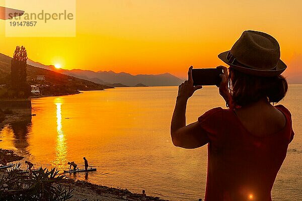 Silhouette einer Frau  die ein Foto bei Sonnenuntergang am Shkoder See in der Gemeinde Shiroka macht  Sommerurlaub. Albanien