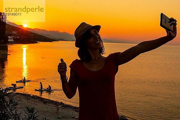 Silhouette einer Frau  die ein Selfie bei Sonnenuntergang am Shkoder See in der Gemeinde Shiroka macht  Sommerurlaub. Albanien