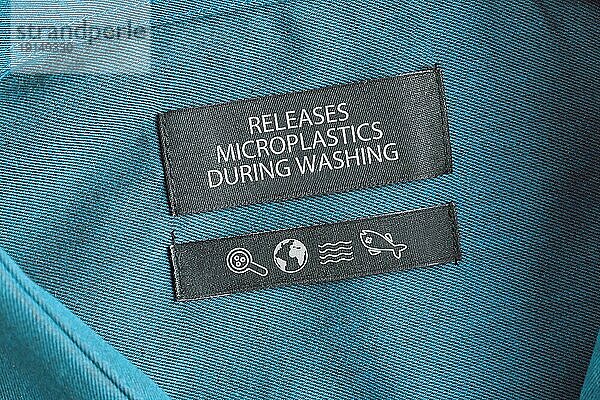 Kleidungsetikett mit der Aufschrift Setzt beim Waschen Mikroplastik frei . Konzept für das Problem der Verschmutzung durch synthetische Bekleidungsfasern