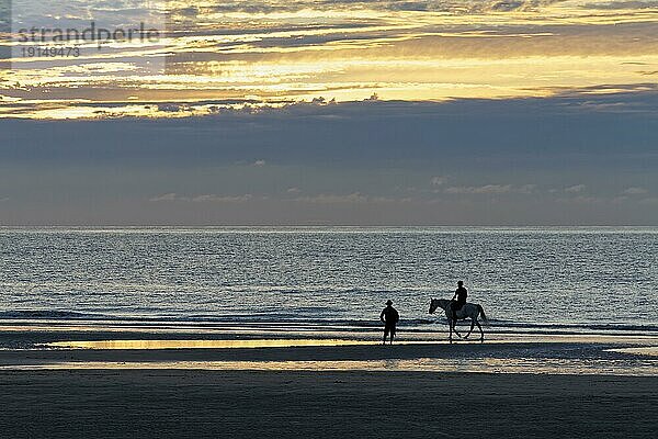 Sonnenuntergang an der belgischen Küste  Silhouette eines Mannes und eines Reiters am Strand  De Haan  Le Coq  Westflandern  Belgien  Europa