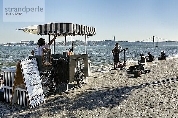 Belebte Terrasse am Ufer des Tejo  Getränkekiosk  Straßenmusiker im Gegenlicht  Ribeira das Naus  Lissabon  Portugal  Europa