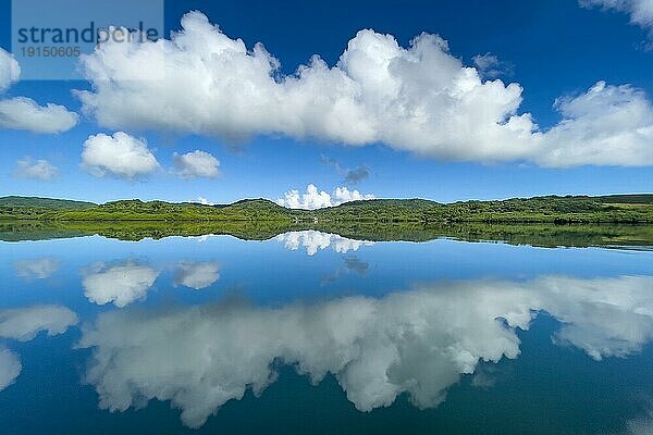 Spiegelung von Wolken Altocumulus vor blauer Himmel spiegeln sich über in Pazifik Stiller Ozean ohne keine Wellen mit in spiegelglatte Meeresoberfläche Wasseroberfläche spiegelglattes Meer  in Bildmitte schmale gespiegelte Silhouette von Südseeinsel mit tropischer grüner Bewuchs tropische Vegetation  Pazifik  Insel Yap  Yap State  Karolineninseln  FSM  Föderierte Staaten von Mikronesien  Australien  Ozeanien