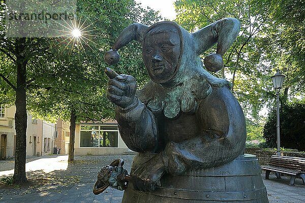 Skulptur Till Eulenspiegel mit Weinfass im Gegenlicht  Narr  Fasching  Weinfass  stehend  herausschauen  blicken  Arm  Zeigefinger  Gestik  zeigen  Hinweis  Richtung  Kitzingen  Unterfranken  Franken  Bayern  Deutschland  Europa