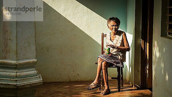 Baracoa  Kuba am 7. Januar 2016: In einem kubanischen Haus genießt eine alte Frau ein Bier in der Sonne