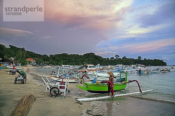 Balinesische Fischer mit traditionellen Ausleger Fischerbooten in der Bucht von Padang Bai  Padangbai  Padang Bay bei Sonnenuntergang auf der Insel Bali  Indonesien  Asien