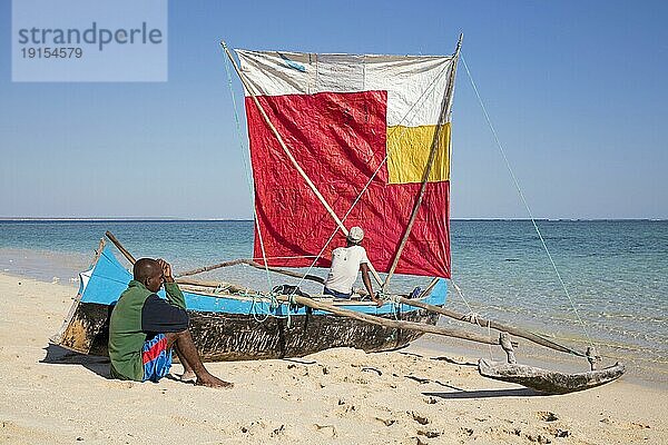 Zwei Fischer mit traditioneller Fischerpiroge mit Segel am Strand von Nosy Ve  Madagaskar  Südostafrika  Afrika