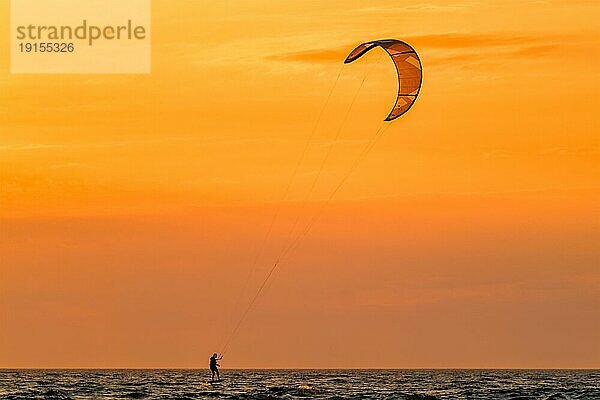 Foiling kiteboarding kitesurfing kiteboarder (kitesurfer) silhouette im Atlantik bei Sonnenuntergang. Strand Fonte da Telha  Costa da Caparica  Portugal  Europa