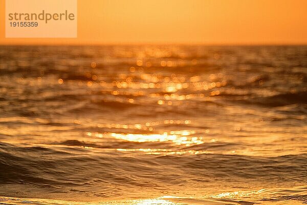 Ozean bei Sonnenuntergang im Gegenlicht mit Sonne defokussiert unscharfen Hintergrund