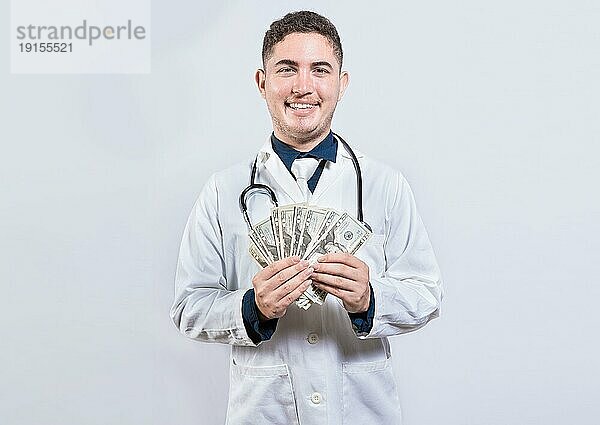 Lateinischer junger Arzt hält Geld isoliert. Fröhlicher Arzt zeigt Dollar isoliert