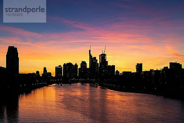 Die Sonne ist hinter der Frankfurter Bankenskyline untergegangen und verfärbt mit ihrem letzten Licht des Tages den Abendhimmel.  Osthafen  Frankfurt am Main  Hessen  Deutschland  Europa