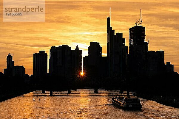 EIn Schiff fährt bei Sonnenuntergang auf dem Main der Silhouette der Frankfurter Bankenskyline entgegen.  Osthafen  Frankfurt am Main  Hessen  Deutschland  Europa