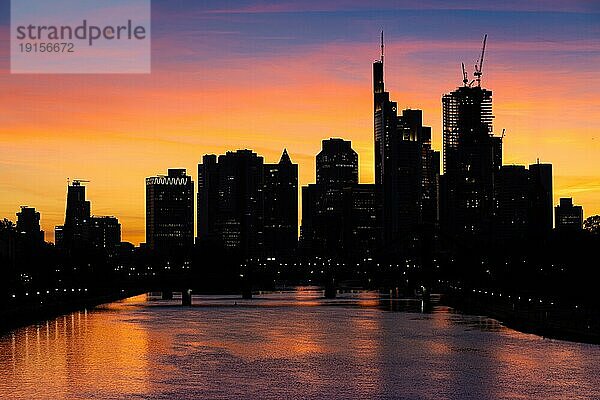 Die Sonne ist hinter der Frankfurter Bankenskyline untergegangen und verfärbt mit ihrem letzten Licht des Tages den Abendhimmel.  Osthafen  Frankfurt am Main  Hessen  Deutschland  Europa