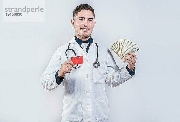 Glücklicher lateinischer Arzt hält Kreditkarte und Geld isoliert. Fröhlicher Arzt hält Geld und Kreditkarten