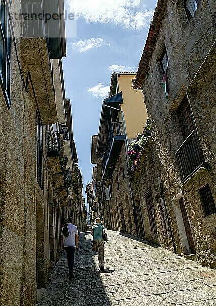 Zwei Personen gehen an Häusern in einer steilen  engen Straße in der mittelalterlichen Stadt Ribadavia  Provinz Ourense  Galicien  Spanien  vorbei  Europa