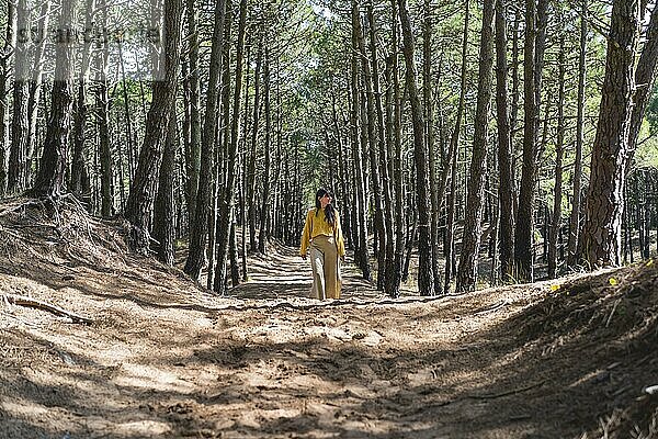 Erwachsene Frau geht über einen Pfad unter den Bäumen im Wald