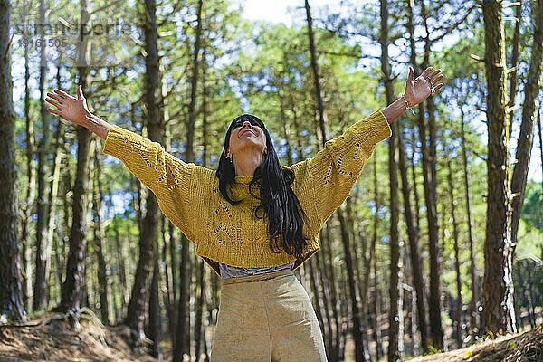 Frau mit offenen Armen  die nach oben schaut  während sie die Natur genießt. Freiheit Konzept