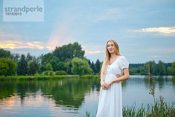 Friedliche junge Frau am Fluss stehend