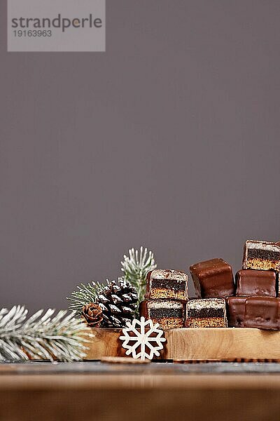 Halbierte traditionelle deutsche Süßigkeiten namens Dominosteine . Weihnachtsbonbon  bestehend aus Lebkuchen  Gelee und Marzipanschichten  überzogen mit Schokoladenglasur auf dunkelgrauem Hintergrund mit negativem Raum