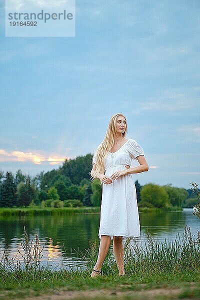 Verträumte junge Frau am Abend am Fluss