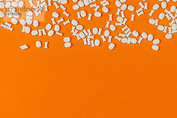 Halloween Hintergrund  Totenköpfe und Knochen in weiß auf Orange  Kopierraum
