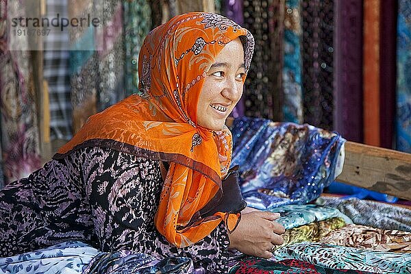 Kirgisische Frau mit Goldzähnen verkauft bunte Stoffe auf dem Markt in Osh  Kirgisistan