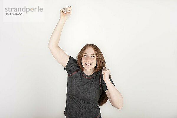 Porträt einer jungen rothaarigen Frau  feiernd  glücklich  mit einem gewinnenden Ausdruck  auf reinem Hintergrund