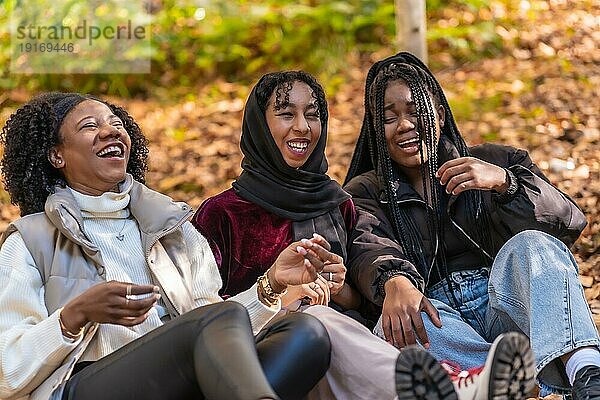 Multikulturelle Gruppe junger Frauen  die in einem Park sitzen und Spaß haben