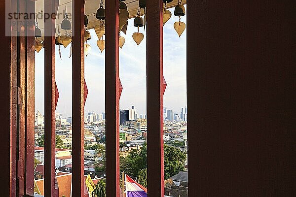 Schönes Stadtbild von Bangkok Stadtzentrum mit blauem Himmel und Wolken  Thailand  durch traditionelle Fenster mit Bars und Glocken mit goldenen Blättern in buddhistischen Tempel von Wat Saket oder Golden Mount. Copyspace Bereich rechts  selektiver Fokus  Asien