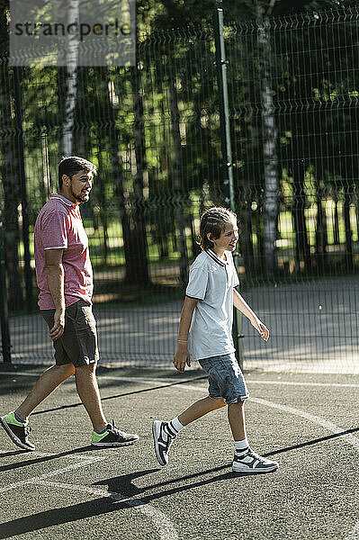 Father and son walking together in basketball court