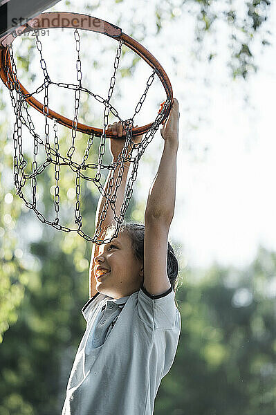 Lächelnder Junge hängt am Basketballkorb
