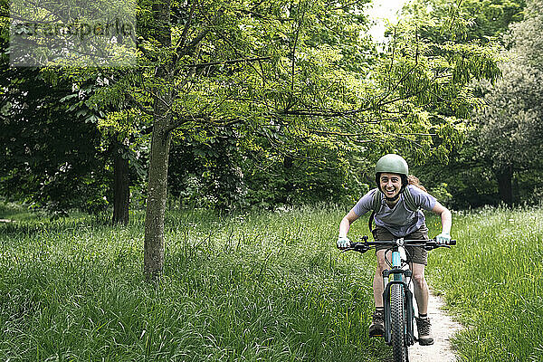 Glückliche Frau fährt Fahrrad inmitten des Fahrrads im Wald