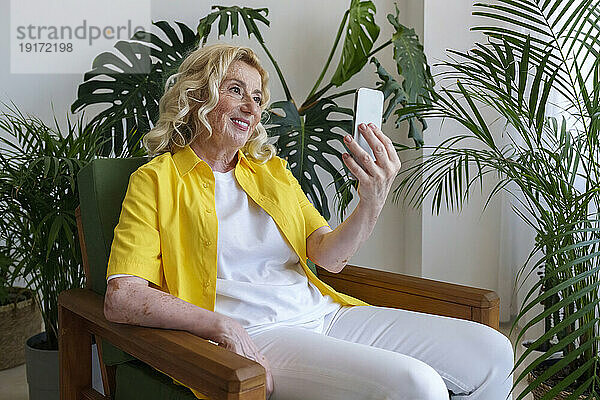 Glückliche ältere Frau  die zu Hause ein Selfie mit dem Smartphone macht
