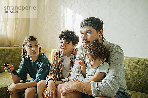 Vater und Kinder schauen zu Hause fern