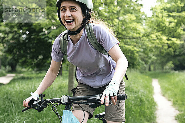 Glückliche Frau genießt das Fahrradfahren im Wald