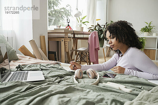 Mädchen mit lockigem Haar macht zu Hause Hausaufgaben