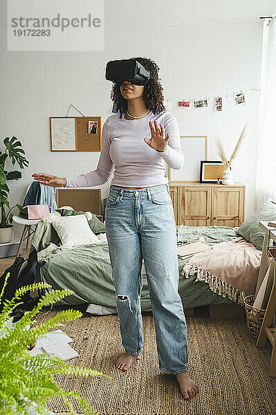 Mädchen mit Virtual-Reality-Simulatoren gestikuliert zu Hause
