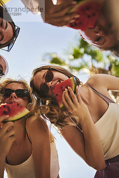 Lächelnde Freunde  die im Urlaub Wassermelone essen