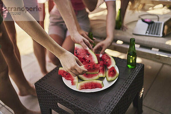 Freunde pflücken am Tisch Wassermelonenscheiben
