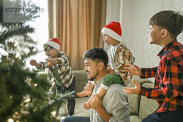 Vater und Söhne amüsieren sich auf dem Sofa neben dem Weihnachtsbaum