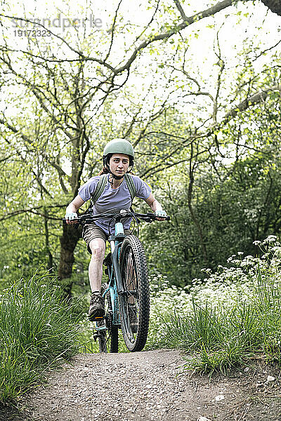 Entschlossene Frau fährt Fahrrad auf Fußweg im Wald