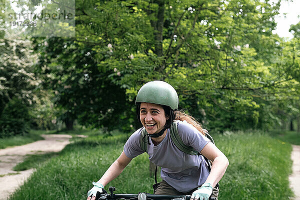 Junge Frau lacht und fährt Fahrrad im Wald