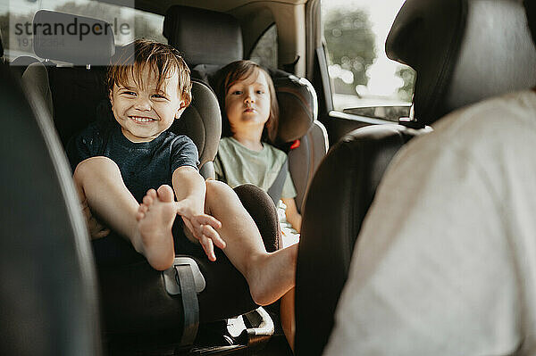 Glücklicher Junge mit Geschwistern und Vater  die im Auto unterwegs sind
