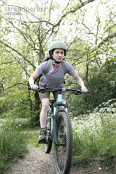 Frau mit Helm fährt Fahrrad im Wald