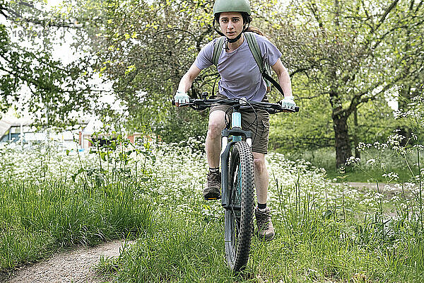 Junge Frau fährt Fahrrad auf Gras im Wald