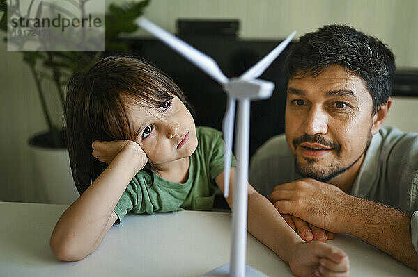 Vater und Sohn betrachten das Modell einer Windkraftanlage auf dem Tisch zu Hause