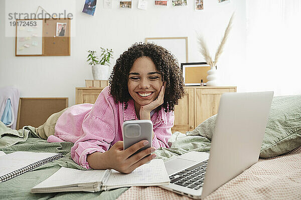Happy teenage girl using smart phone at home