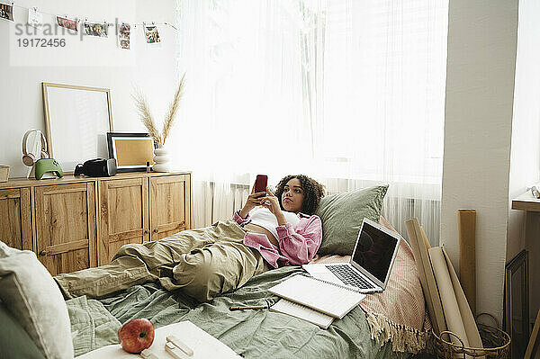 Teenager-Mädchen benutzt Smartphone  das zu Hause im Bett liegt